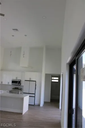 a view of kitchen with stainless steel appliances wooden floor and window