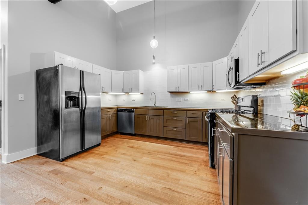 10 Walnut Street, Unit 7 Pittsburgh, PA 15202 - Photo 5 of 49 a kitchen with stainless steel appliances granite countertop a stove a sink dishwasher a refrigerator and a microwave oven with wooden floor