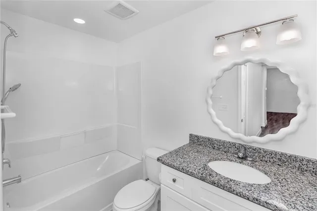 a bathroom with a granite countertop sink a toilet and bathtub