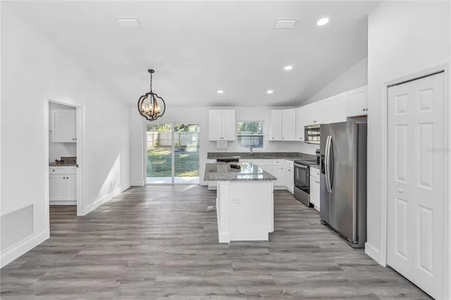 a kitchen with stainless steel appliances granite countertop a refrigerator a microwave oven a sink and dishwasher with wooden floor