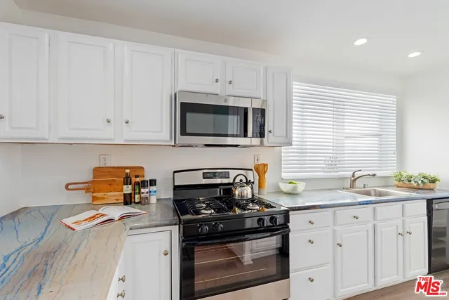 a kitchen with stainless steel appliances granite countertop white cabinets a stove a sink and dishwasher