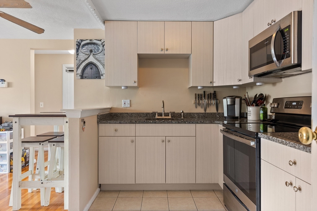 145 Warren Street, Unit 8 Watertown, MA 02472 - Photo 6 of 10 a kitchen with granite countertop white cabinets and stainless steel appliances