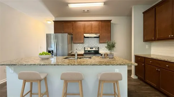 a kitchen with stainless steel appliances granite countertop a sink and a refrigerator