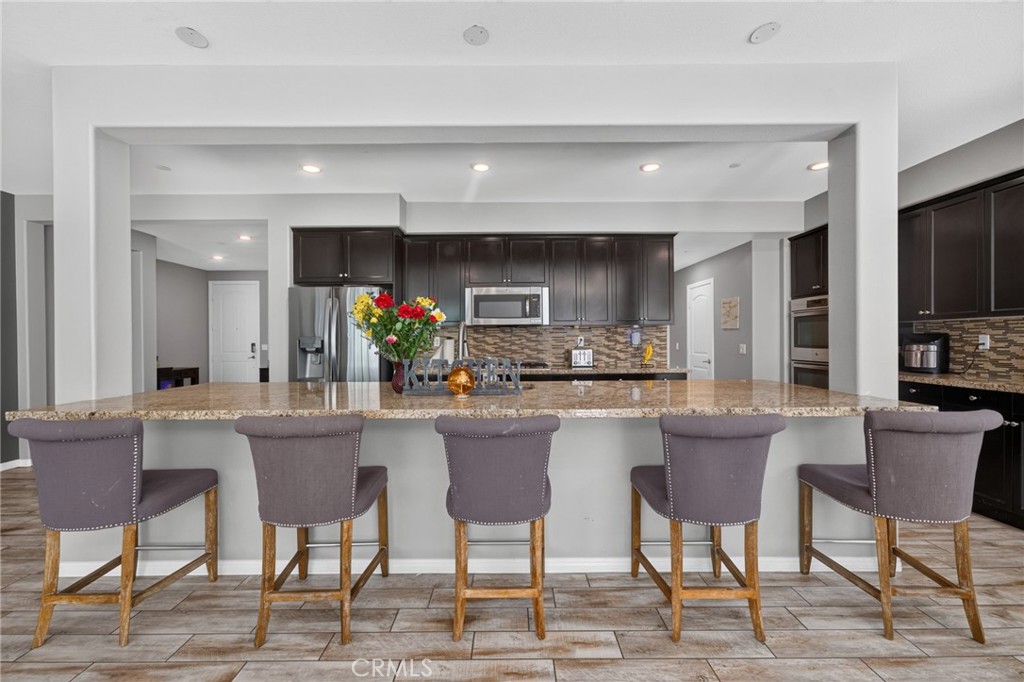 23347 Crystal Way Wildomar, CA 92595 - Photo 23 of 109 a kitchen with a dining table chairs and a refrigerator