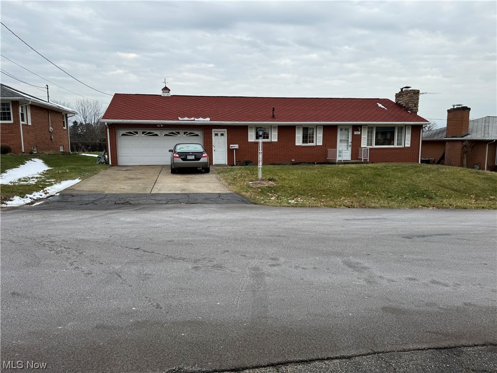 Ranch-style house featuring a front yard and a garage