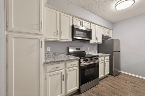 a kitchen with stainless steel appliances granite countertop a stove top oven microwave and refrigerator