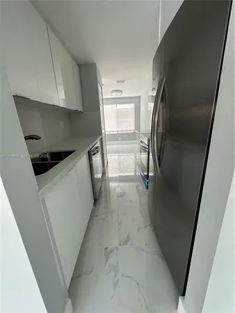 a hallway with white cabinets and stainless steel appliances