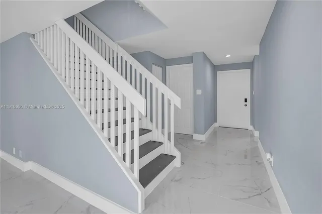 a view of staircase with railing and white walls