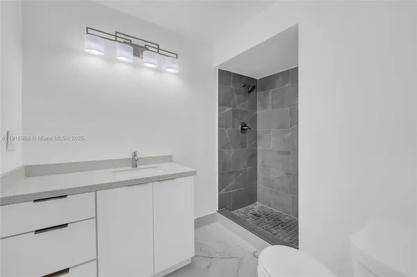 a bathroom with a granite countertop sink a toilet and shower