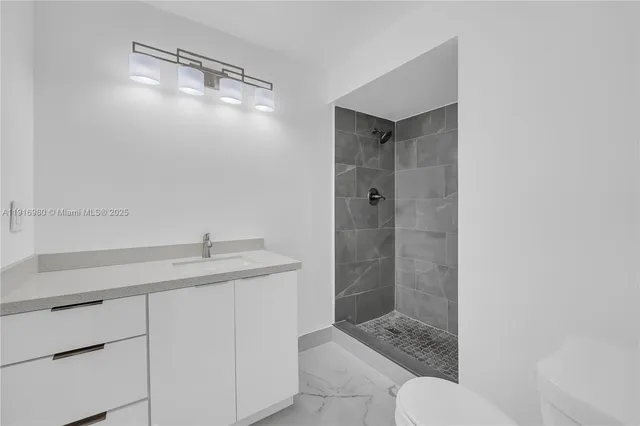 a bathroom with a granite countertop sink a toilet and shower