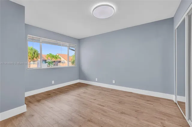 a view of an empty room with window and wooden floor