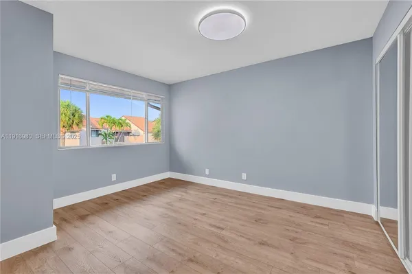 a view of an empty room with window and wooden floor