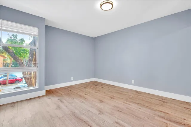 a view of an empty room with wooden floor and window
