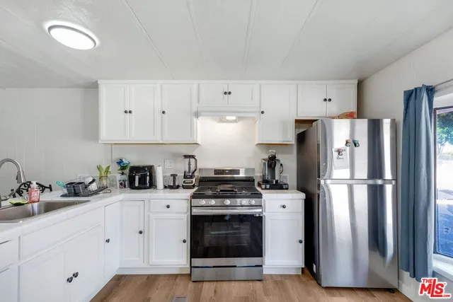 a kitchen with refrigerator a stove a sink and white cabinets