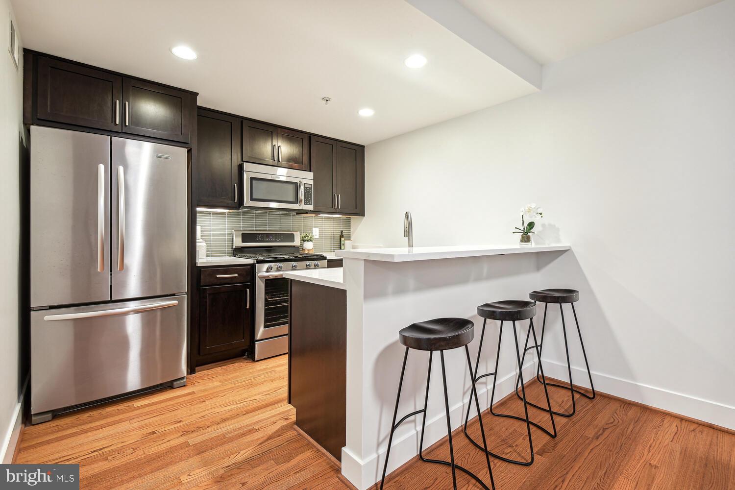 1317 Shepherd Street Northwest, Unit A Washington, DC 20011 - Photo 9 of 17 a kitchen with stainless steel appliances granite countertop a refrigerator a stove a sink and a microwave