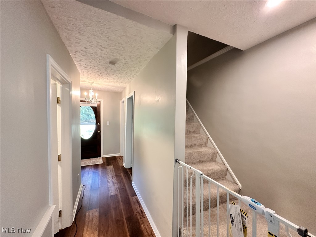8145 Chagrin Road Chagrin Falls, OH 44023 - Photo 25 of 40 Hallway with a textured ceiling, dark wood-style flooring, a chandelier, and stairs