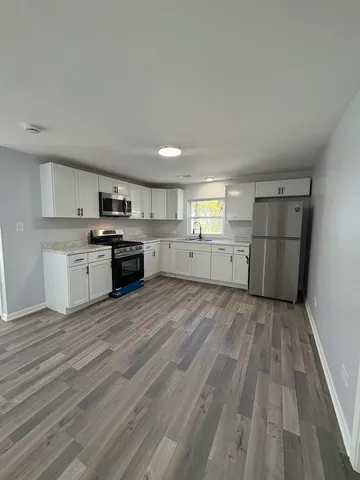 a large kitchen with a wooden floor and stainless steel appliances
