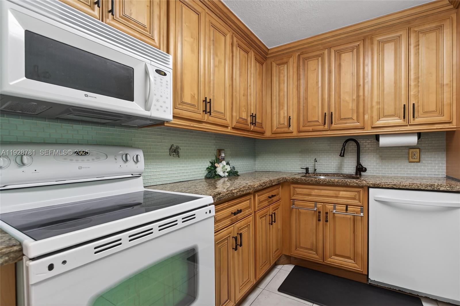 6195 Rock Island Road, Unit 103 Tamarac, FL 33319 - Photo 7 of 27 a kitchen with stainless steel appliances granite countertop a sink and a microwave