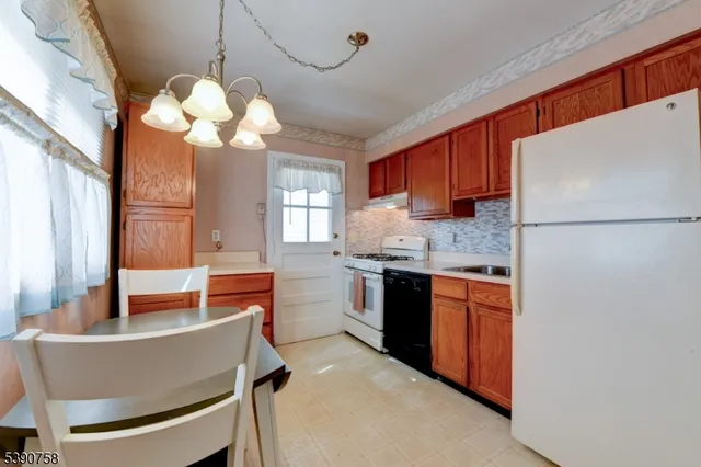 a kitchen with a refrigerator a stove a sink cabinets and a dining table