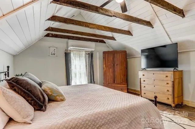 a bedroom with a bed and a flat tv screen on wall