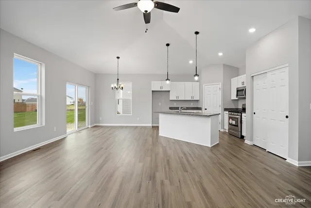 a large kitchen with stainless steel appliances granite countertop a sink a stove a refrigerator and island with wooden floor