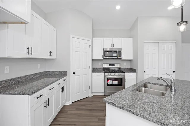 a kitchen with granite countertop a sink a counter top space and cabinets