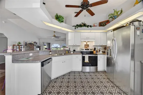 a kitchen with stainless steel appliances kitchen island granite countertop a refrigerator a sink a stove and white cabinets
