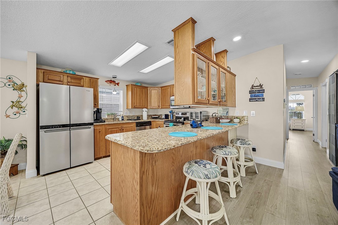 2991 Sloop Lane St. James City, FL 33956 - Photo 14 of 43 a kitchen with stainless steel appliances granite countertop a refrigerator a sink dishwasher a stove with white cabinets and wooden floor