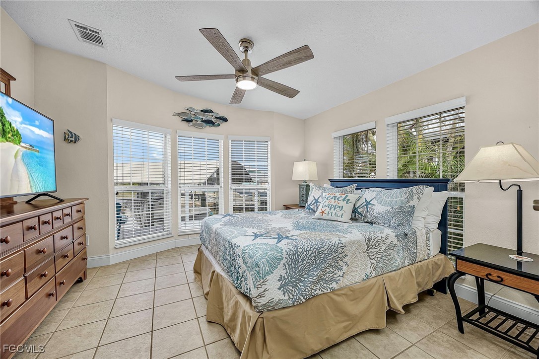 2991 Sloop Lane St. James City, FL 33956 - Photo 26 of 43 a bedroom with a large bed and a flat tv screen on dresser