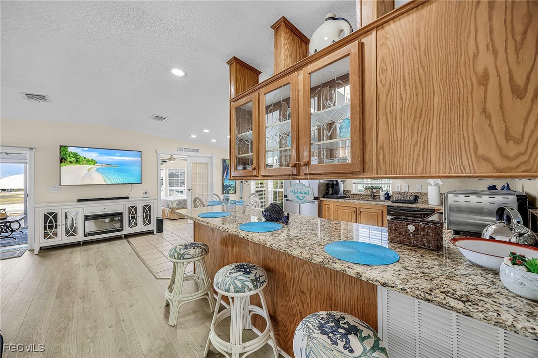 2991 Sloop Lane St. James City, FL 33956 - Photo 29 of 43 a kitchen with stainless steel appliances granite countertop a stove a sink dishwasher and cabinets with wooden floor