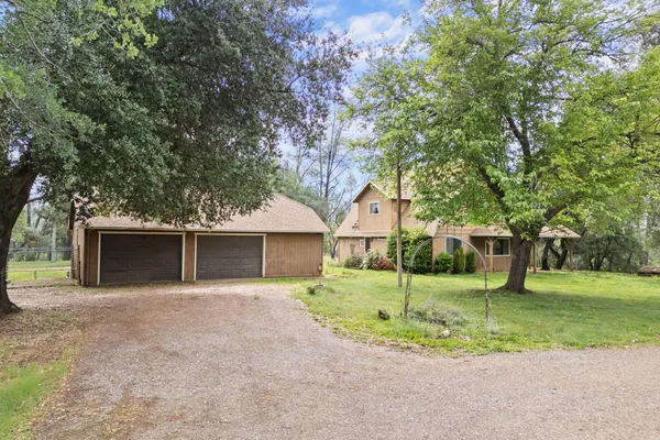 a view of a house with a yard and large tree