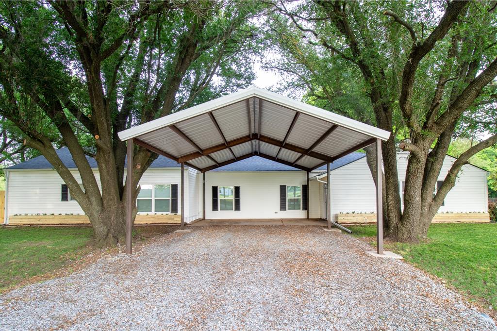 View of front facade with driveway, a front yard, and a carport