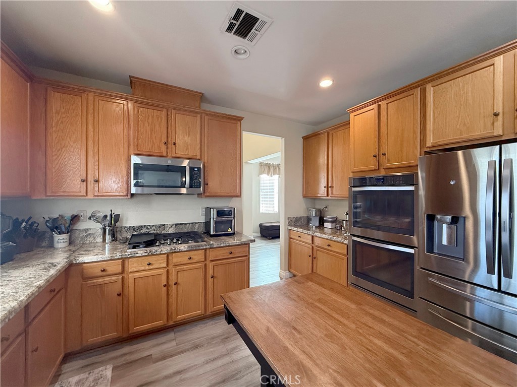 23964 Old Pomegranate Road Yorba Linda, CA 92887 - Photo 5 of 30 a kitchen with stainless steel appliances granite countertop a refrigerator a stove top oven a sink and dishwasher with wooden floor