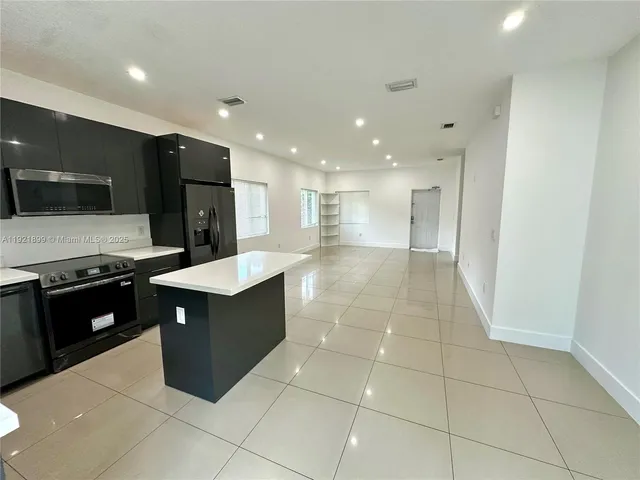 a large kitchen with stainless steel appliances a large counter top and a stove