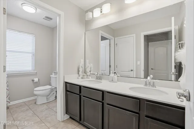 a bathroom with a double vanity sink toilet and a mirror