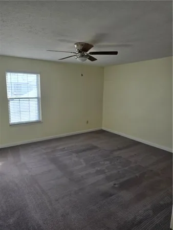 an empty room with windows and fan