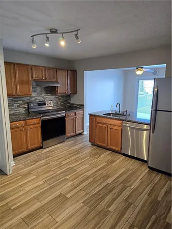 a kitchen with stainless steel appliances granite countertop a sink a stove top oven and cabinetry