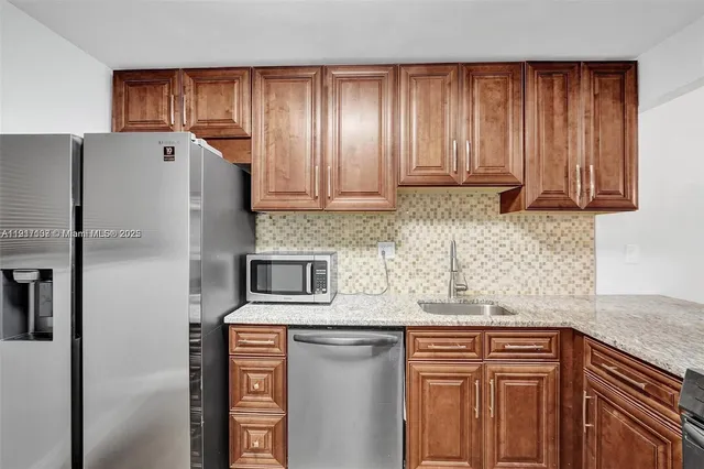 a kitchen with stainless steel appliances granite countertop a refrigerator and a sink