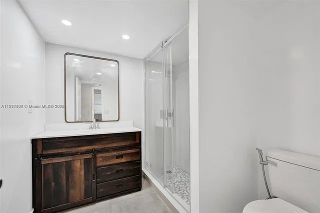 a bathroom with a sink a toilet a mirror and shower