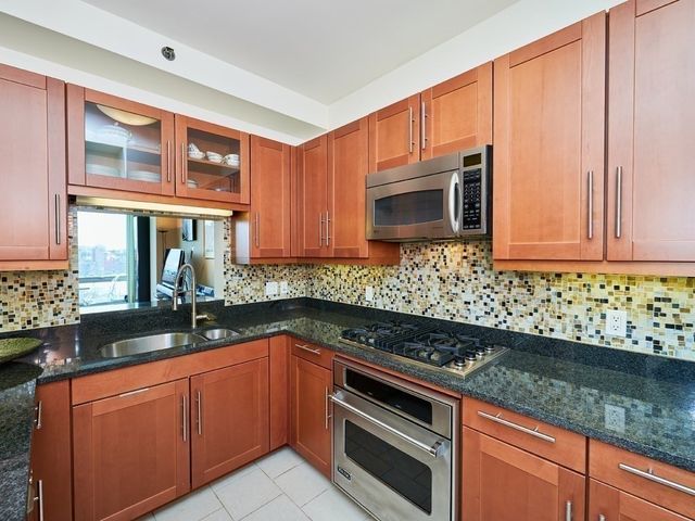 a kitchen with granite countertop stainless steel appliances a sink stove and microwave