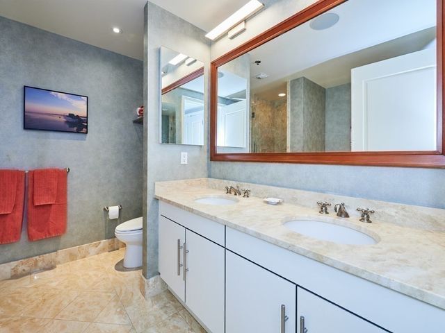 a bathroom with a granite countertop sink a toilet and a mirror