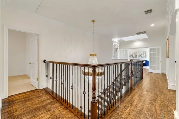 a view of a hallway with wooden floor and a chandelier