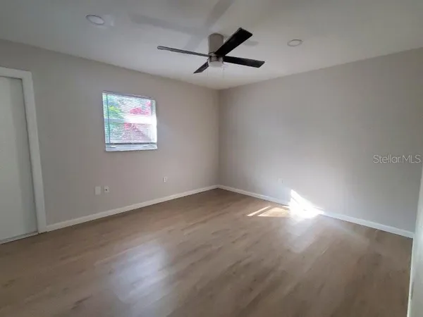 a view of a big room with wooden floor a ceiling fan and windows