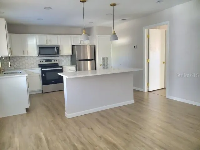 a kitchen with stainless steel appliances granite countertop a refrigerator a stove top oven a sink and dishwasher