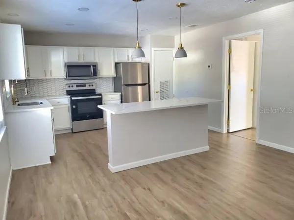 a kitchen with stainless steel appliances granite countertop a refrigerator a stove top oven a sink and dishwasher with wooden floor