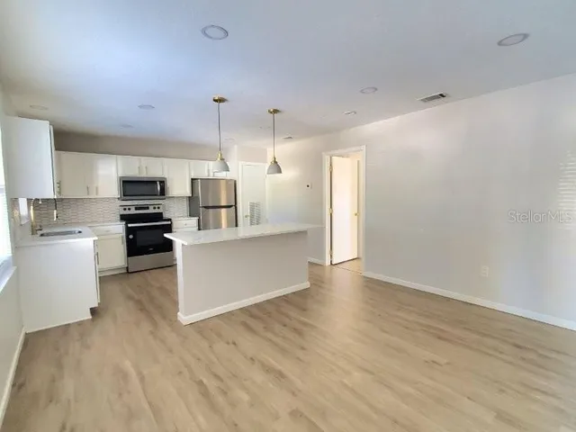 a kitchen with kitchen island white cabinets and stainless steel appliances