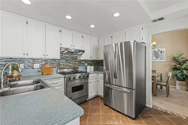 a kitchen with stainless steel appliances granite countertop a refrigerator a stove and a sink