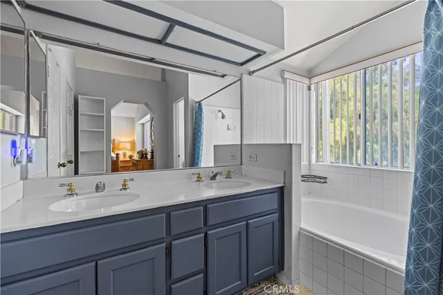 a bathroom with a tub a sink and mirror