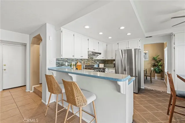 a kitchen with stainless steel appliances a refrigerator a stove a sink and white cabinets with wooden floor