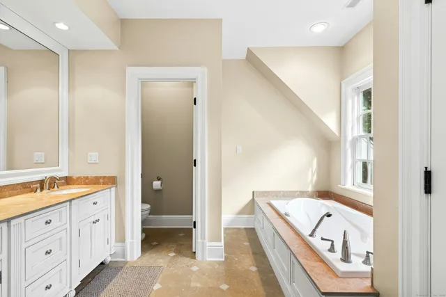 a spacious bathroom with a double vanity sink a large mirror and a bathtub